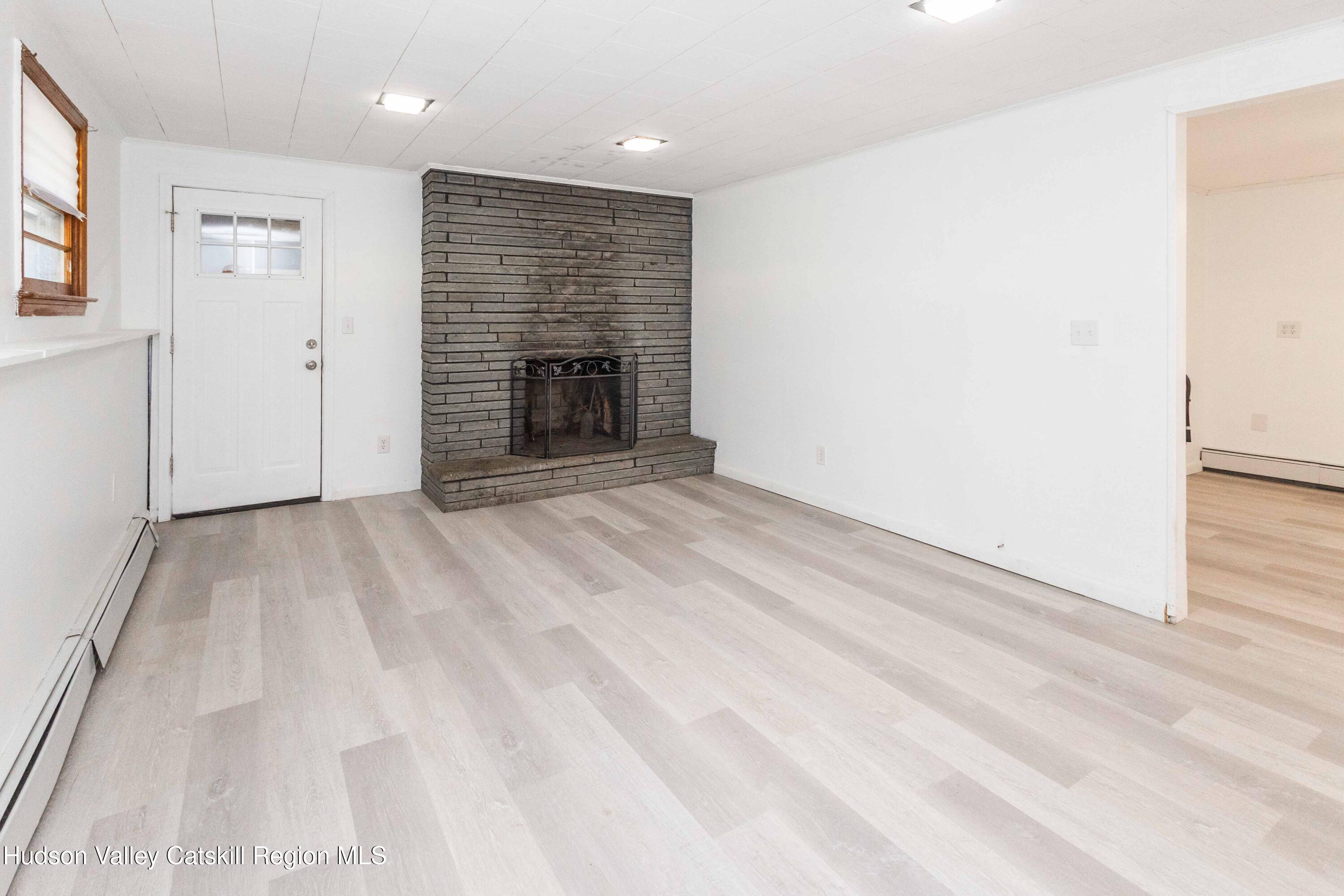 94 Lodge Road Saugerties, NY 12477 - Photo 35 of 47 en empty room with wooden floor and fireplace