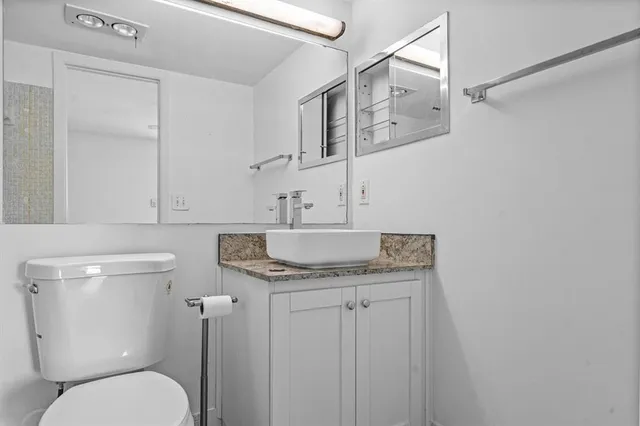 a bathroom with a granite countertop toilet sink and mirror