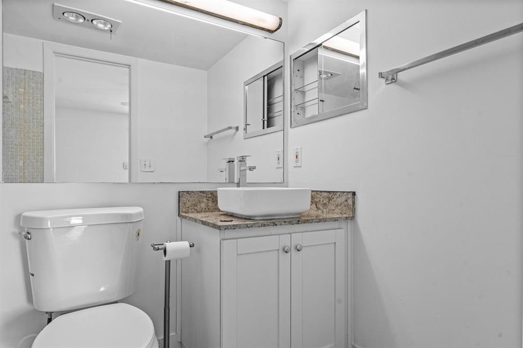 1038 Cambridge B, Unit 1038 Deerfield Beach, FL 33442 - Photo 13 of 22 a bathroom with a granite countertop toilet sink and mirror
