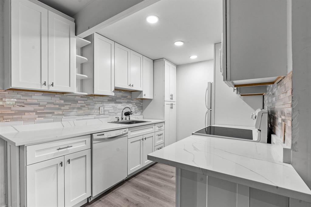 1038 Cambridge B, Unit 1038 Deerfield Beach, FL 33442 - Photo 2 of 22 a kitchen with a sink dishwasher and white cabinets with wooden floor