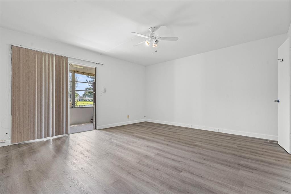 1038 Cambridge B, Unit 1038 Deerfield Beach, FL 33442 - Photo 7 of 22 a view of an empty room with wooden floor and a window