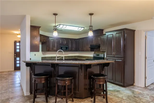 a kitchen with granite countertop wooden cabinets and a stove top oven