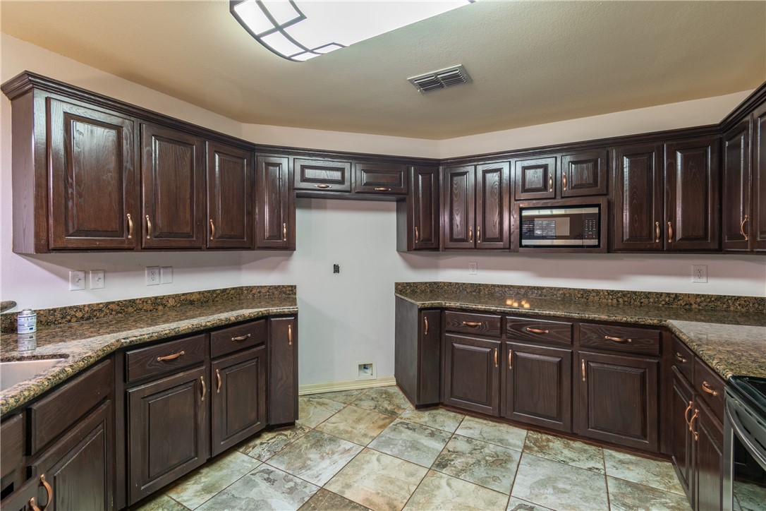 204 County Road 1331 Alice, TX 78332 - Photo 9 of 30 a kitchen with granite countertop wooden cabinets and a stove top oven