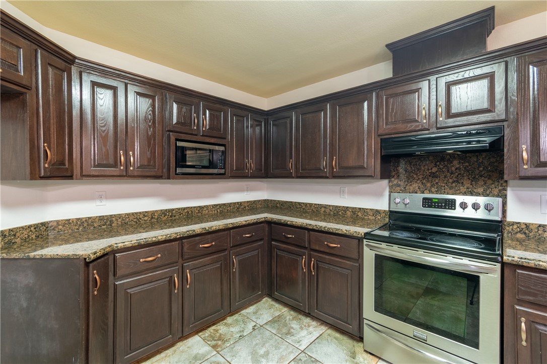204 County Road 1331 Alice, TX 78332 - Photo 10 of 30 a kitchen with granite countertop wooden cabinets and stainless steel appliances