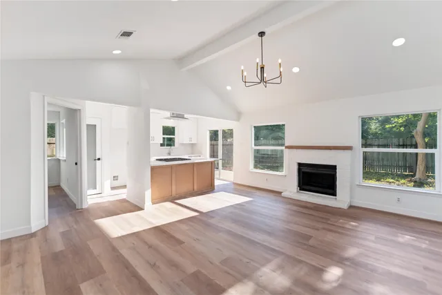 a view of a livingroom with a fireplace wooden floor and chandelier