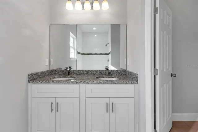 a bathroom with a granite countertop sink and a mirror