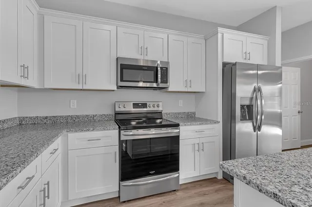 a kitchen with white cabinets and stainless steel appliances