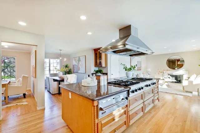 a kitchen with stainless steel appliances granite countertop a stove and a view of living room