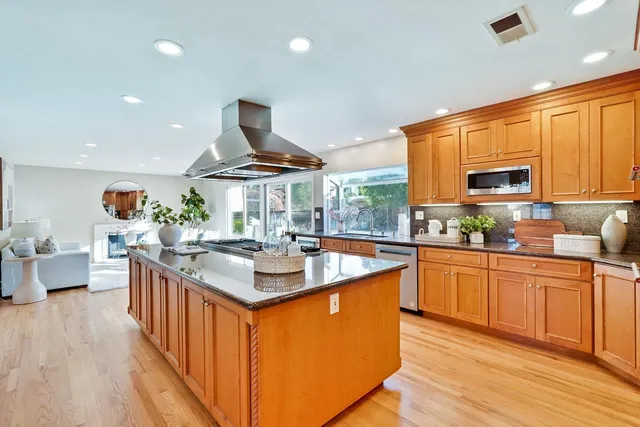 a kitchen with stainless steel appliances granite countertop a sink stove and wooden cabinets