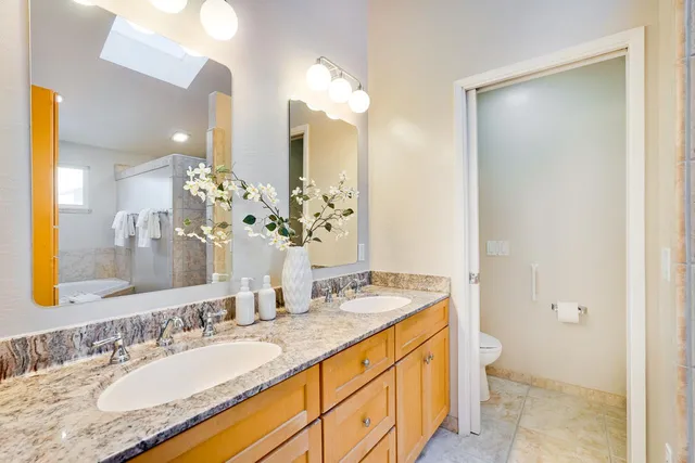 a bathroom with a granite countertop double vanity sink and a mirror