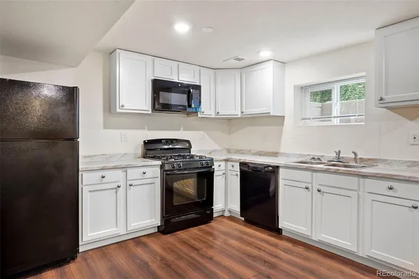 a kitchen with granite countertop white cabinets stainless steel appliances and sink
