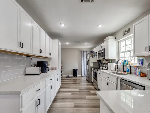 a large white kitchen with lots of counter space a refrigerator and a stove top oven