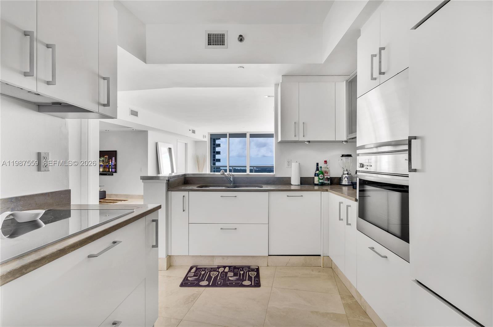 450 Alton Road, Unit 2005 Miami Beach, FL 33139 - Photo 7 of 19 a kitchen with granite countertop white cabinets and white appliances