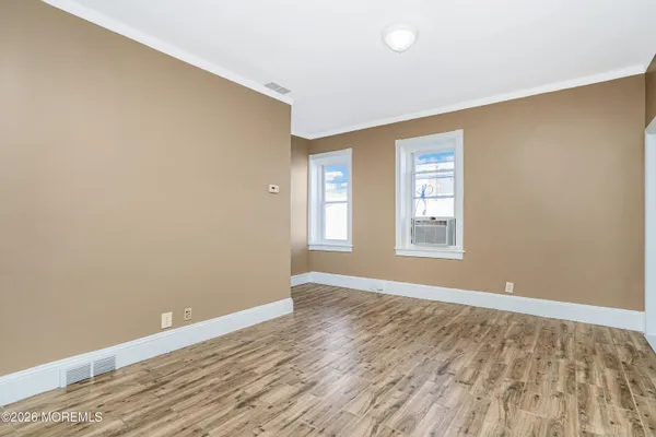 an empty room with wooden floor and windows