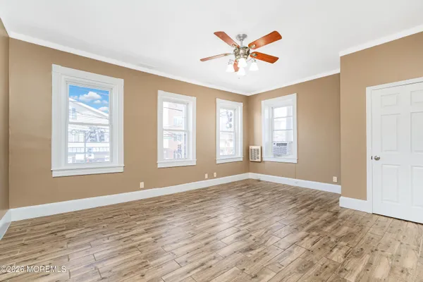 a view of an empty room with window and wooden floor