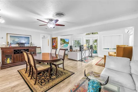 a living room with furniture a dining table and paintings on the wall with wooden floor