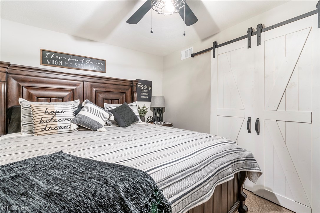 3792 South Raccoon Road Canfield, OH 44406 - Photo 20 of 39 Carpeted bedroom featuring a barn door and ceiling fan
