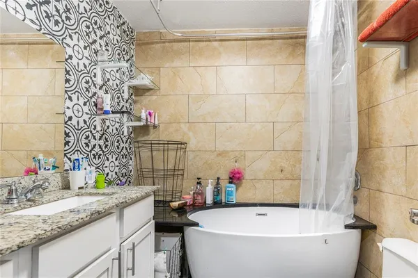 a bathroom with a granite countertop sink and a bathtub