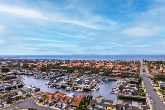 an aerial view of a city with lots of residential buildings ocean and mountain view in back