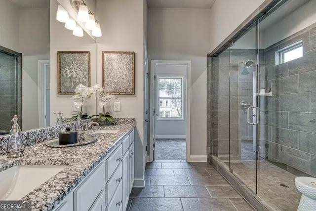 a bathroom with a granite countertop sink a mirror and a shower