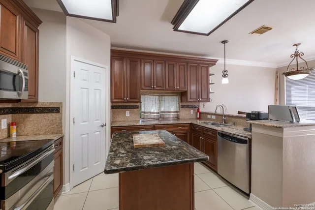 a kitchen with kitchen island granite countertop a sink stove and refrigerator