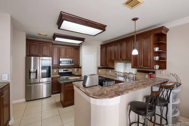 a kitchen with stainless steel appliances granite countertop a stove a sink and a refrigerator