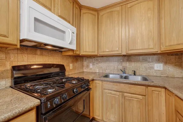 a kitchen with stainless steel appliances granite countertop a stove a sink dishwasher and cabinets with wooden floor