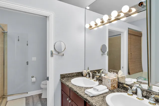 a bathroom with a granite countertop sink a toilet and a mirror