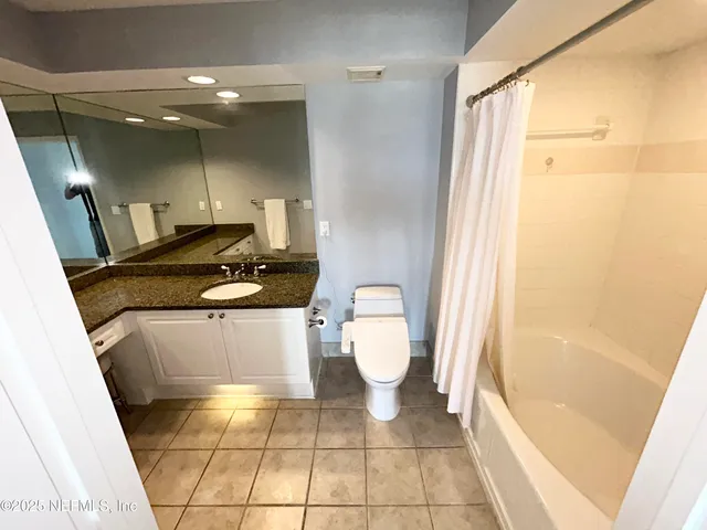 a bathroom with a granite countertop sink a toilet a mirror and bathtub