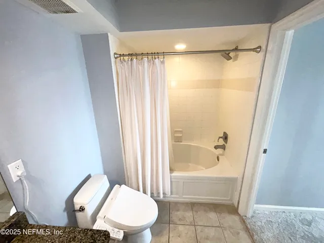 a bathroom with a granite countertop bathtub shower and toilet