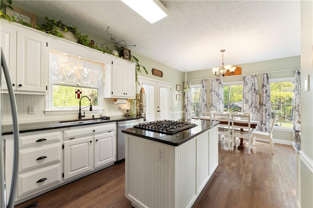 402 Hunters Court Ball Ground, GA 30107 - Photo 10 of 56 a kitchen with stainless steel appliances a stove a sink and white cabinets with wooden floor