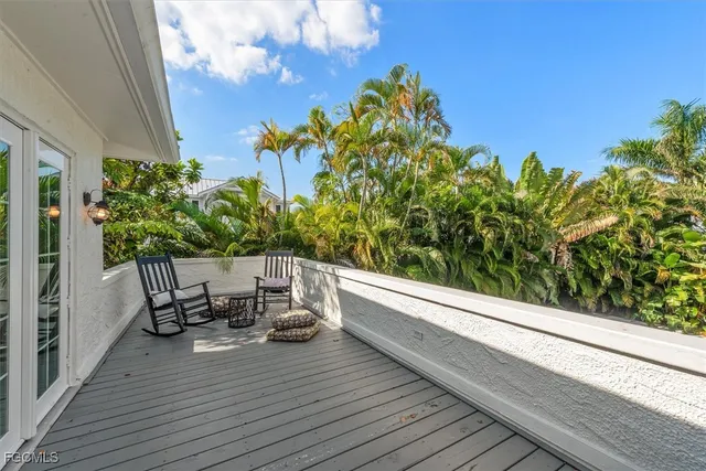 a view of a balcony with chairs and wooden fence