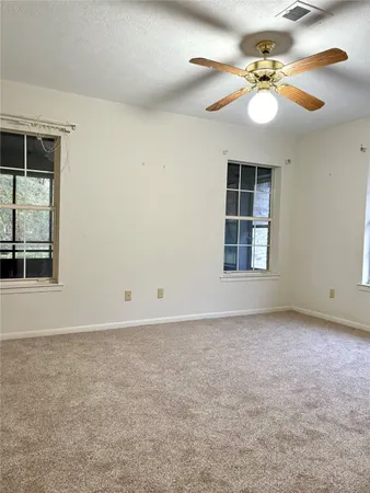 an empty room with windows and fan