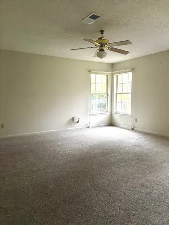 en empty room with windows and ceiling fan