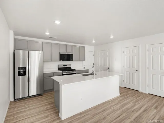 a kitchen with stainless steel appliances a refrigerator stove and wooden floor