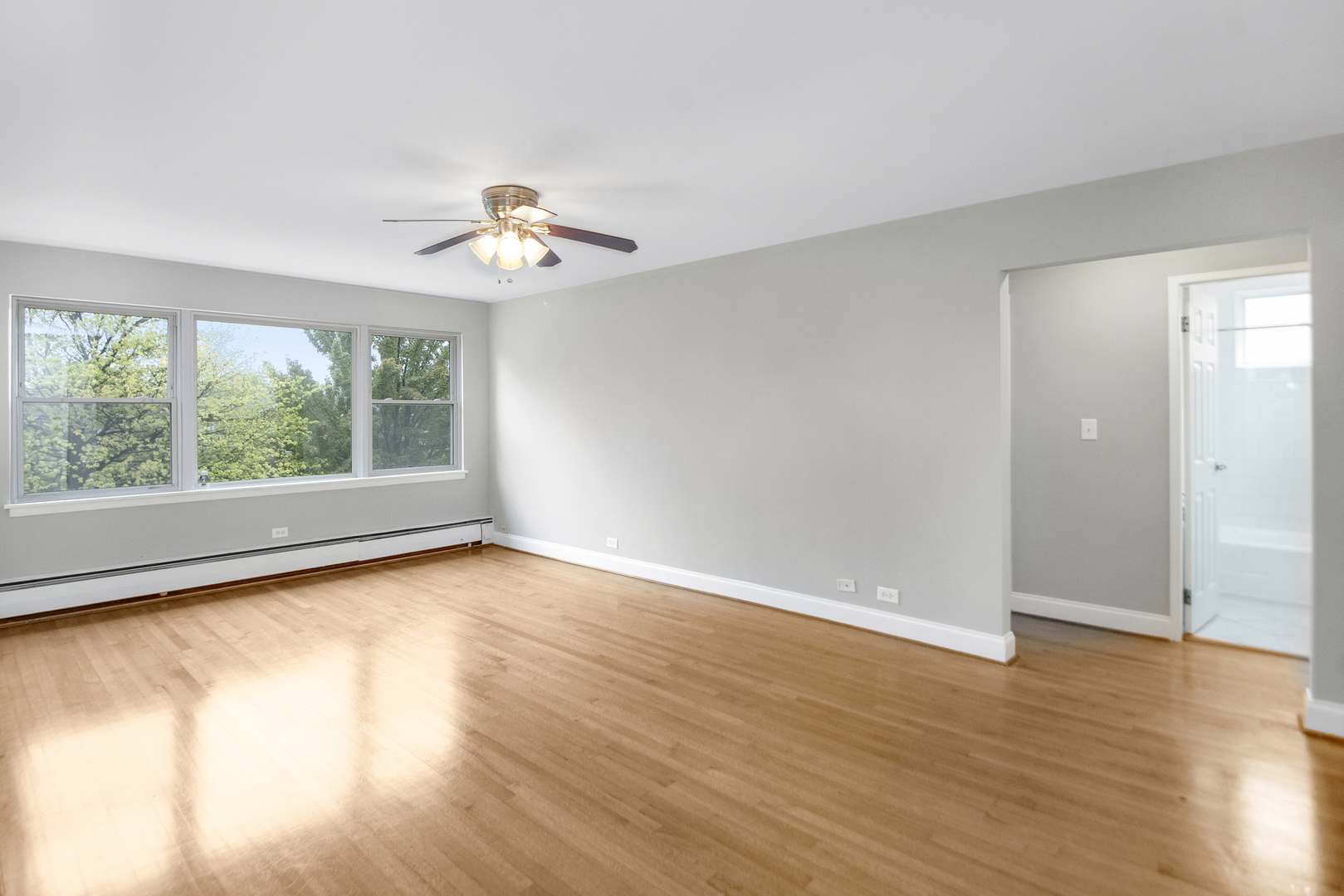 1951 Euclid Avenue, Unit 202 Berwyn, IL 60402 - Photo 8 of 16 an empty room with wooden floor chandelier fan and windows