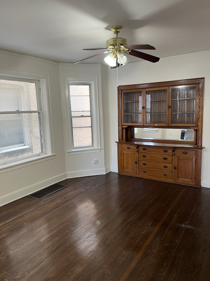 3741 West Irving Park Road, Unit 1 Chicago, IL 60618 - Photo 3 of 8 a view of an empty room with wooden floor and fan