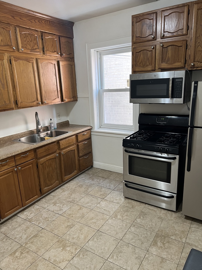 3741 West Irving Park Road, Unit 1 Chicago, IL 60618 - Photo 7 of 8 a kitchen with stainless steel appliances a stove sink and cabinets