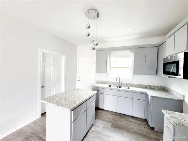 a kitchen with a sink dishwasher a stove and white cabinets with wooden floor