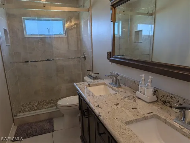 a bathroom with a granite countertop sink a toilet and a mirror