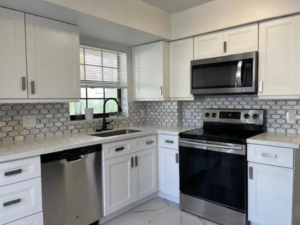 a large kitchen with a stove a sink dishwasher and a microwave oven on the granite countertops