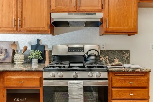 a kitchen with stainless steel appliances granite countertop a stove a sink and a microwave