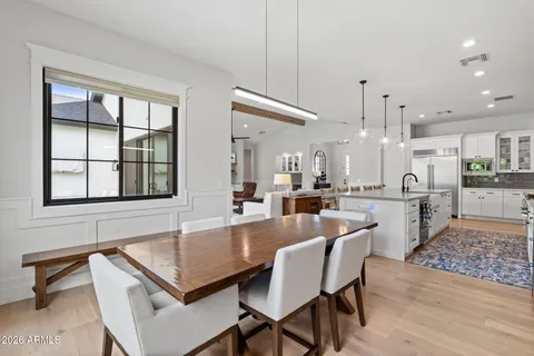 a dining hall with stainless steel appliances kitchen island granite countertop a dining table chairs and a large window