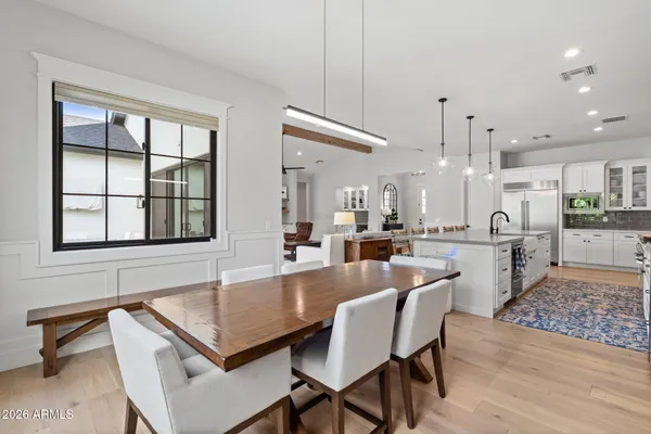 a dining hall with stainless steel appliances kitchen island granite countertop a dining table chairs and a large window