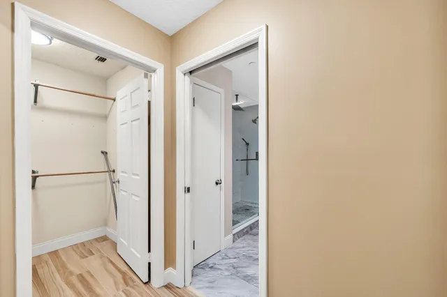 a view of a lake with lawn chairs and large trees