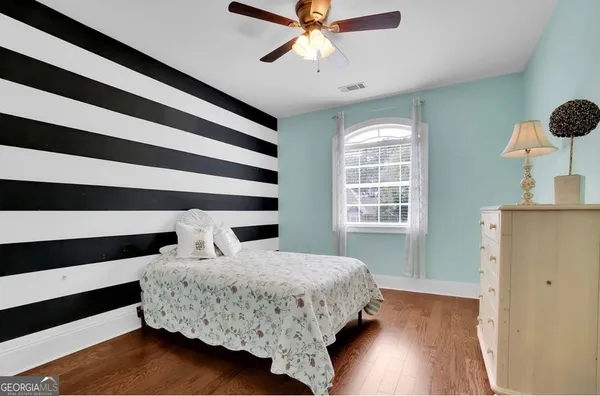 a view of an empty room with chandelier fan and wooden floor
