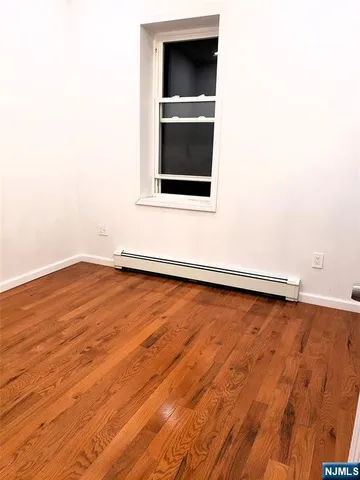 an empty room with wooden floor and cabinet