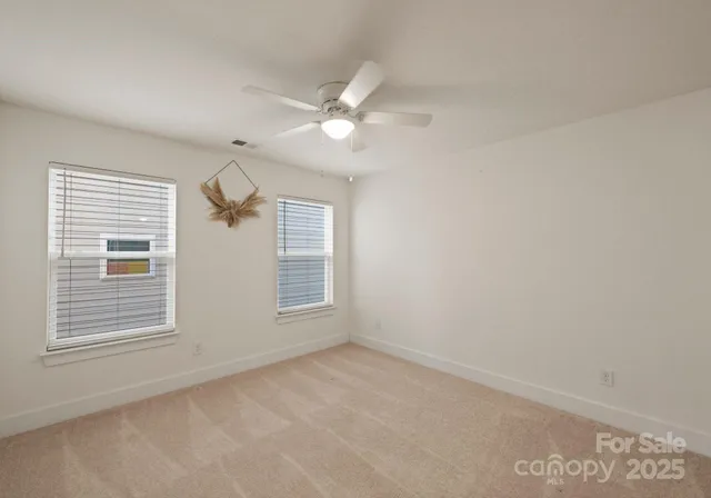 an empty room with chandelier fan and windows