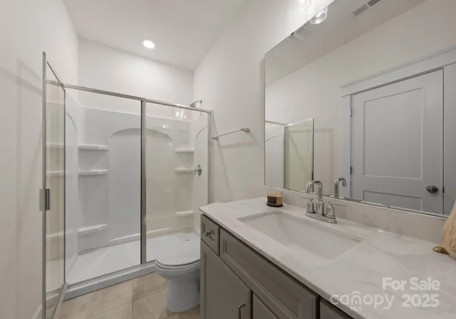 a bathroom with a granite countertop sink a toilet and shower