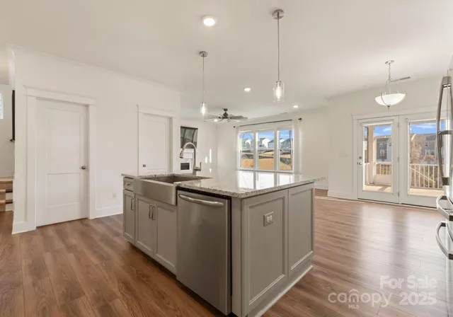 a kitchen with stainless steel appliances granite countertop a sink a stove and a wooden floors